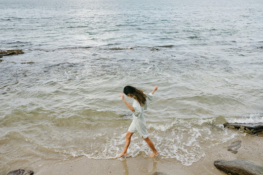 Model in Loungewear Skipping across Sand and Water