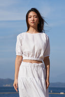 Model wearing batwing cropped top in white on beach