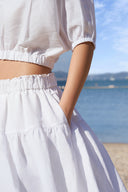 Model wearing high-waisted tiered maxi skirt in white, close up of waistband