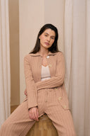 Model wearing wide leg pants in soft suede paired with cardigan sitting on stool