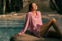 Woman in a pink striped cotton Terry set sitting by a pool