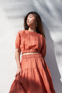 Model wearing high-waisted tiered maxi skirt in terracotta