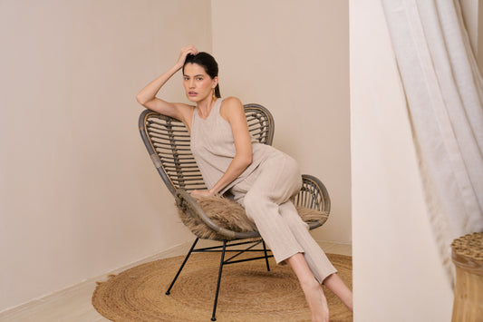 Model wearing ribbed tank paired with tapered pant lounging on chair