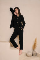 Model wearing tapered pant in black paired with ribbed tank and cardigan against wall
