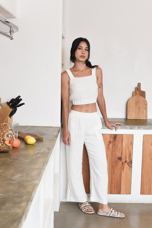 Model wearing crinkle white cropped tank and lounge pants in kitchen