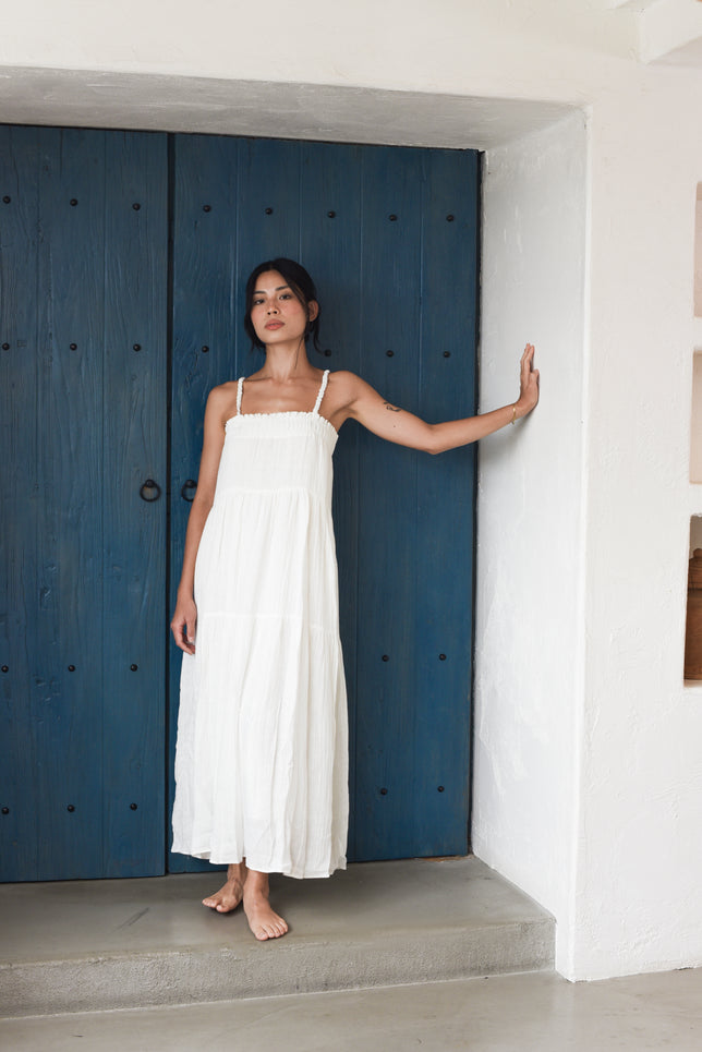 Model wearing crinkle white linen maxi dress against blue door