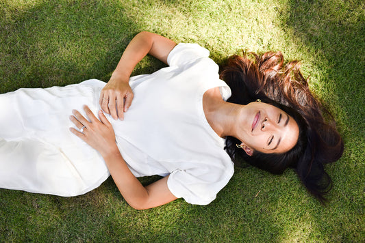 SoL loungewear founder Lois Tien lying in the grass smiling in the sunshine