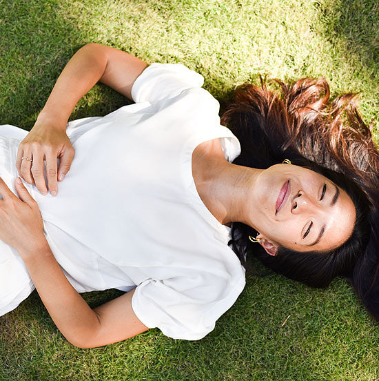 SOL loungewear founder Lois Tien lying in the grass smiling in the sunshine